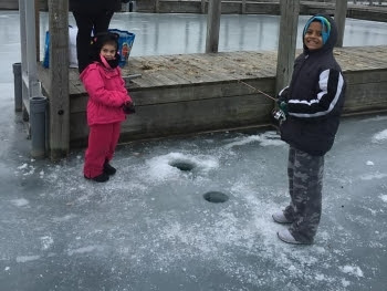 two kids ice fishing near dock