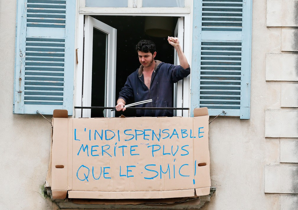 Homem coloca placa improvisada com a mensagem ‘O essencial merece mais do que um salário mínimo’, na cidade de Bayonne, no sudeste da França, nesta sexta-feira, 1º de Maio — Foto: Bob Edme/AP