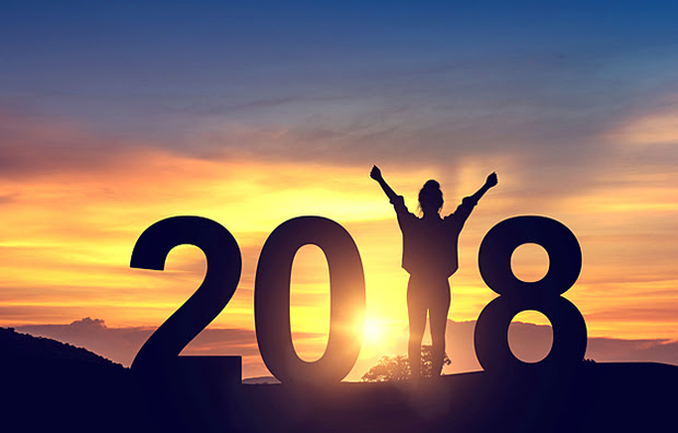 A woman as the 1 in 2018 facing the sunrise and lifting her arms in celebration.