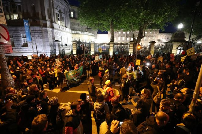 Hundreds of rebels outside the gates of the Irish parliament at night.