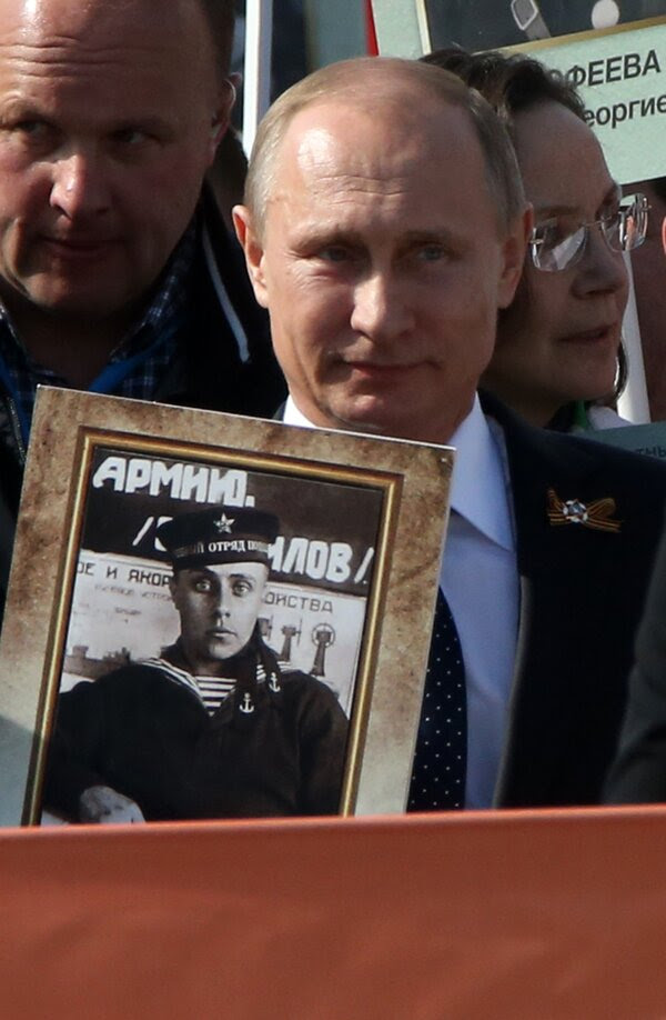 手持父親照片的普京，攝於2015年。中國的紀錄片讚揚普京重振了俄羅斯對該國過去的自豪感。