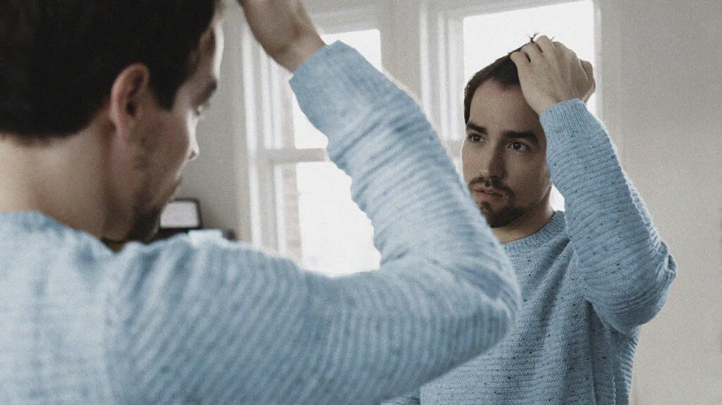 a person looking at their hair in a mirror