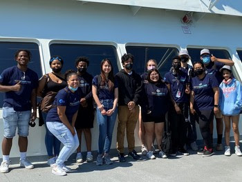 Thirteen youth posing for a photo on the outdoor deck of a ferry