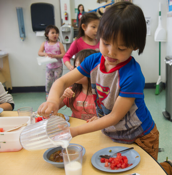 A boy pours a glass of milk to have with his lunch.