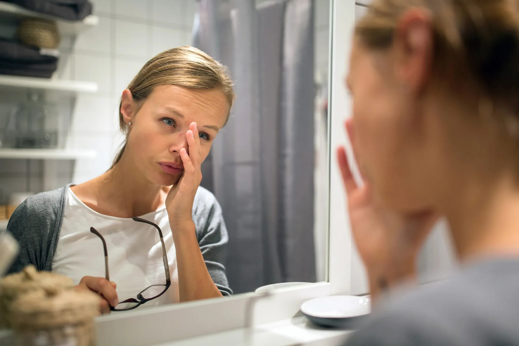 tired young woman looking in the mirror