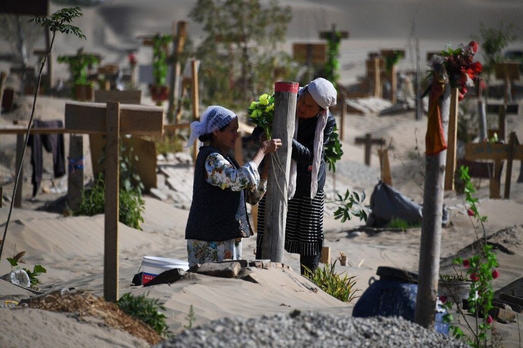 Des femmes décorant une tombe dans un cimetière ouïghour à la périphérie de Hotan dans la région du Xinjiang. | Greg Baker / AFP