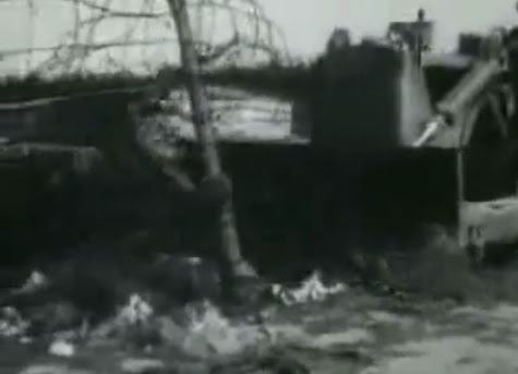A bulldozer flattening Bergen Belsen camp                         cutting the barbed wire fence (27min. 58sec.)