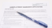 An unemployment insurance application form with a pen