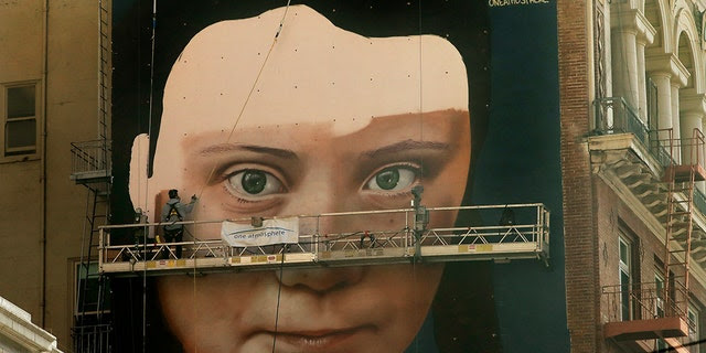 Andres Petreselli paints a mural on the side of a building depicting Swedish teen climate activist Greta Thunberg, Friday, Nov. 8, 2019, in San Francisco. (AP Photo/Ben Margot)