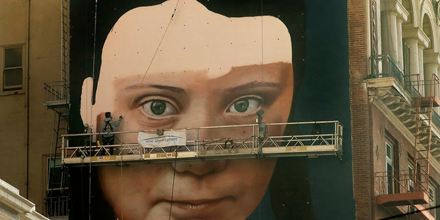 Andres Petreselli paints a mural on the side of a building depicting Swedish teen climate activist Greta Thunberg, Friday, Nov. 8, 2019, in San Francisco. (AP Photo/Ben Margot)