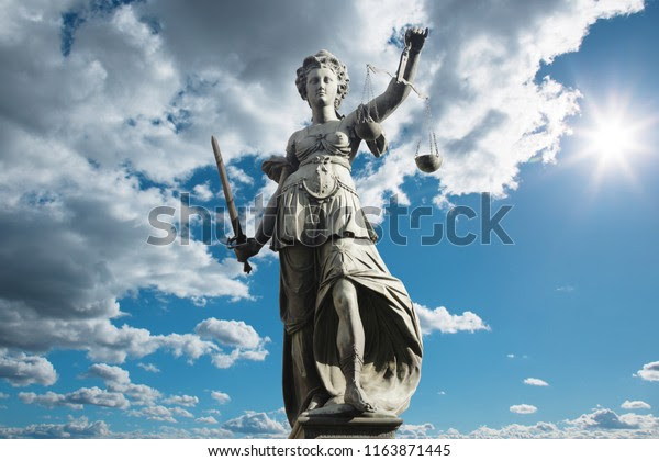 Justitia symbol of justice in front of background with sky and clouds. Concept of justice and law.