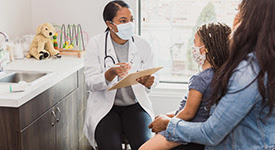 Health care provider talking to child on a parent's lap