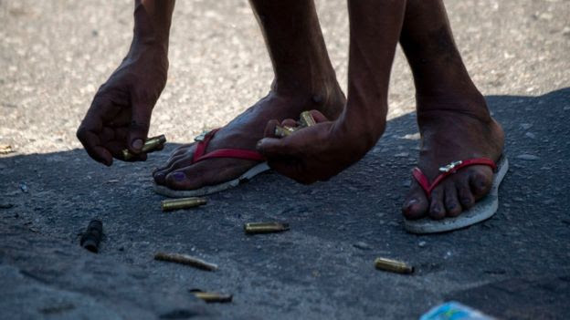 Pessoa junta cartuchos de arma de fogo no Rio de Janeiro.