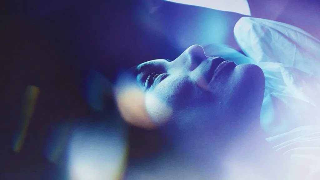 shot of woman staring at the ceiling, blue-ish hue