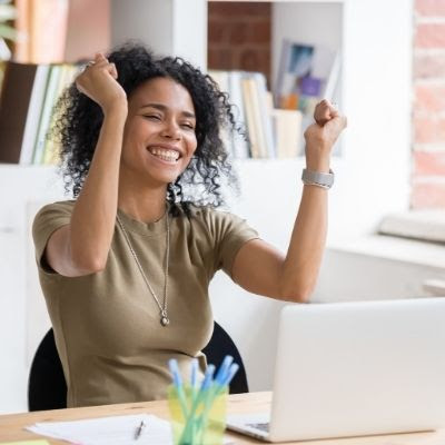 Black woman rejoicing at a laptop