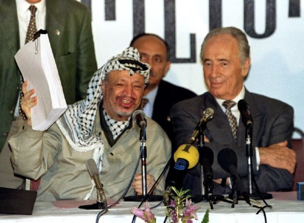 Yasser Arafat waves the second Oslo agreement as Shimon Peres looks on