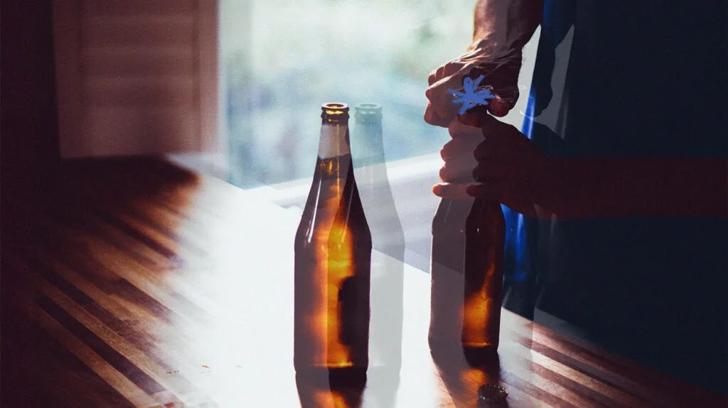 A man opening the cap of the beer bottle with a bottle opener