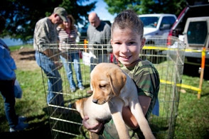 girl in camo holds a golden retriever puppy