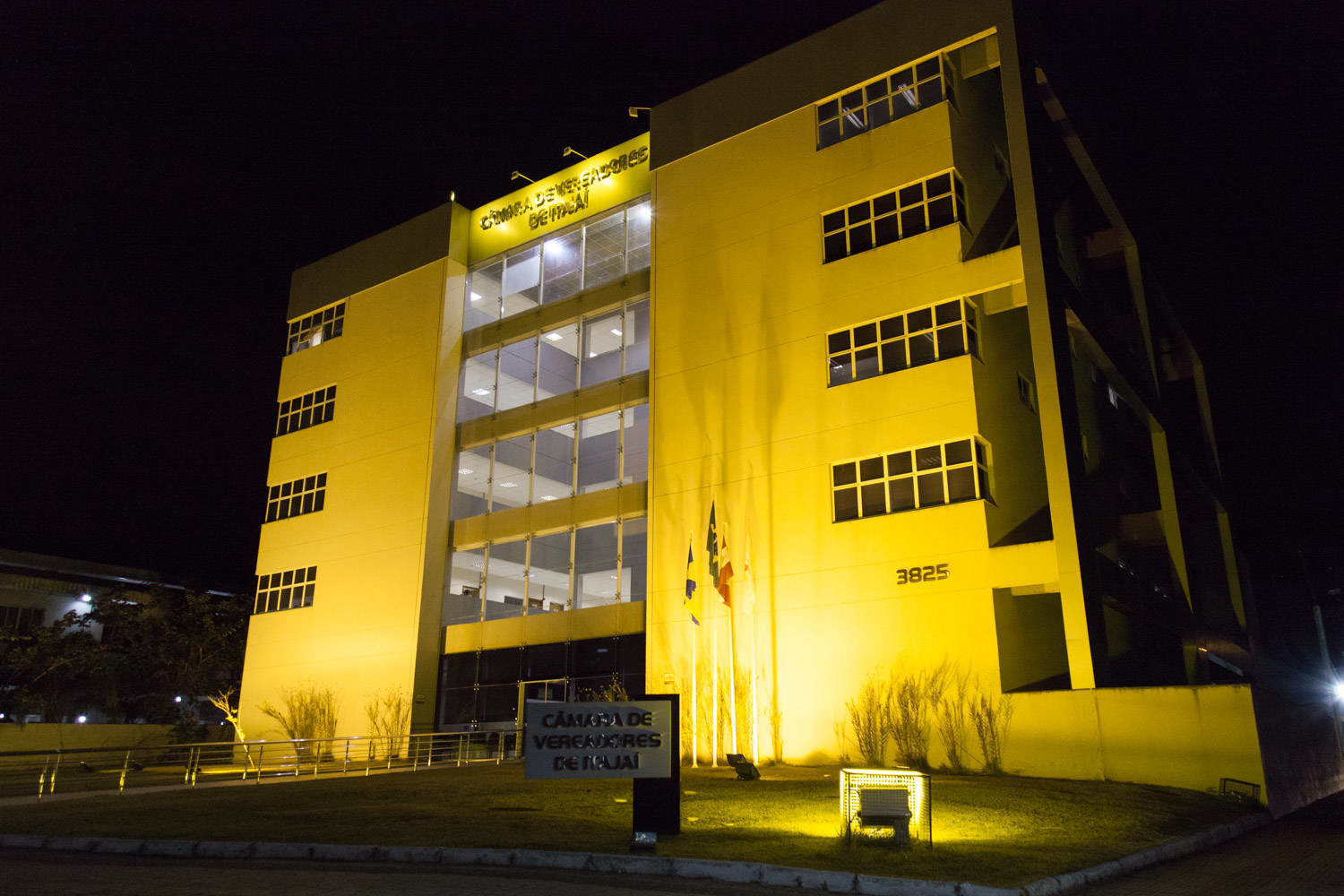 #PraCegoVer a foto mostra a fachada da
Câmara de Itajaí à noite, iluminada com a cor
amarela.