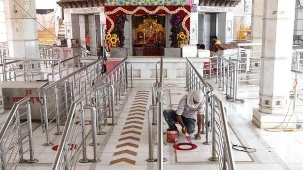 
A man paints circles on the floor of a temple for devotees to maintain social distancing in New Delhi on June 6, 2020. 