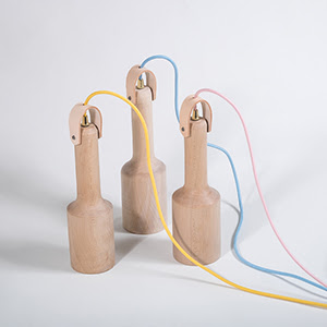 A product photograph of three hanging lights made in wood, with each a different pastel colour cable, yellow, blue and pink. 