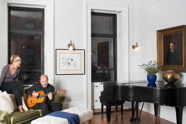 Rubén Blades y Luba Mason en su sala de estar con una obra de Al Hirschfeld que muestra a Blades en <em>The Capeman</em> y una pintura de un artista desconocido.