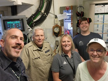 Five people posing for a selfie in the engine room of a ferry