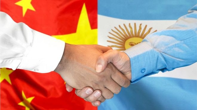 Aperto de mãos em frente a bandeiras da China e da Argentina