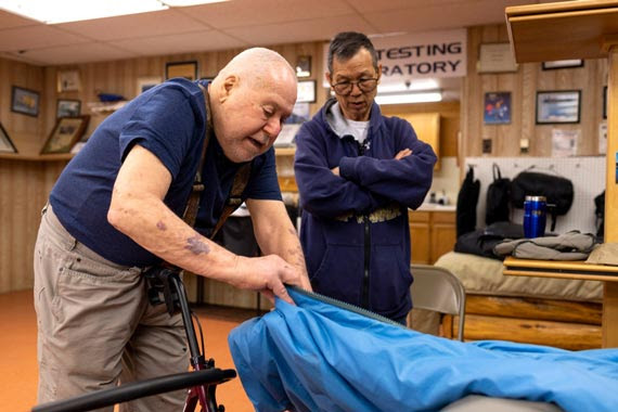 Two men inspecting a blue sleeping bag