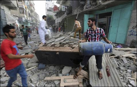Unos hombres observan los daños en un edificio destruído durante un atáque aéreo del ejército israelí en la ciudad de Gaza.