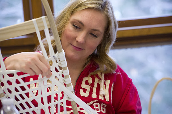 A close-up view shows a woman making snowshoes.