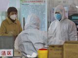 Medical workers in protective gear talk with a woman suspected of being ill with a coronavirus at a community health station in Wuhan in central China&#39;s Hubei Province, Monday, Jan. 27, 2020. China on Monday expanded sweeping efforts to contain a viral disease by extending the Lunar New Year holiday to keep the public at home and avoid spreading infection. (Chinatopix via AP)