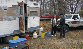 A conservation officer talks with a hunter at a deer camp.