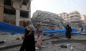 Mujeres palestinas caminando entre los escombros en el barrio de Nasr, en la ciudad de Gaza. (Archivo)