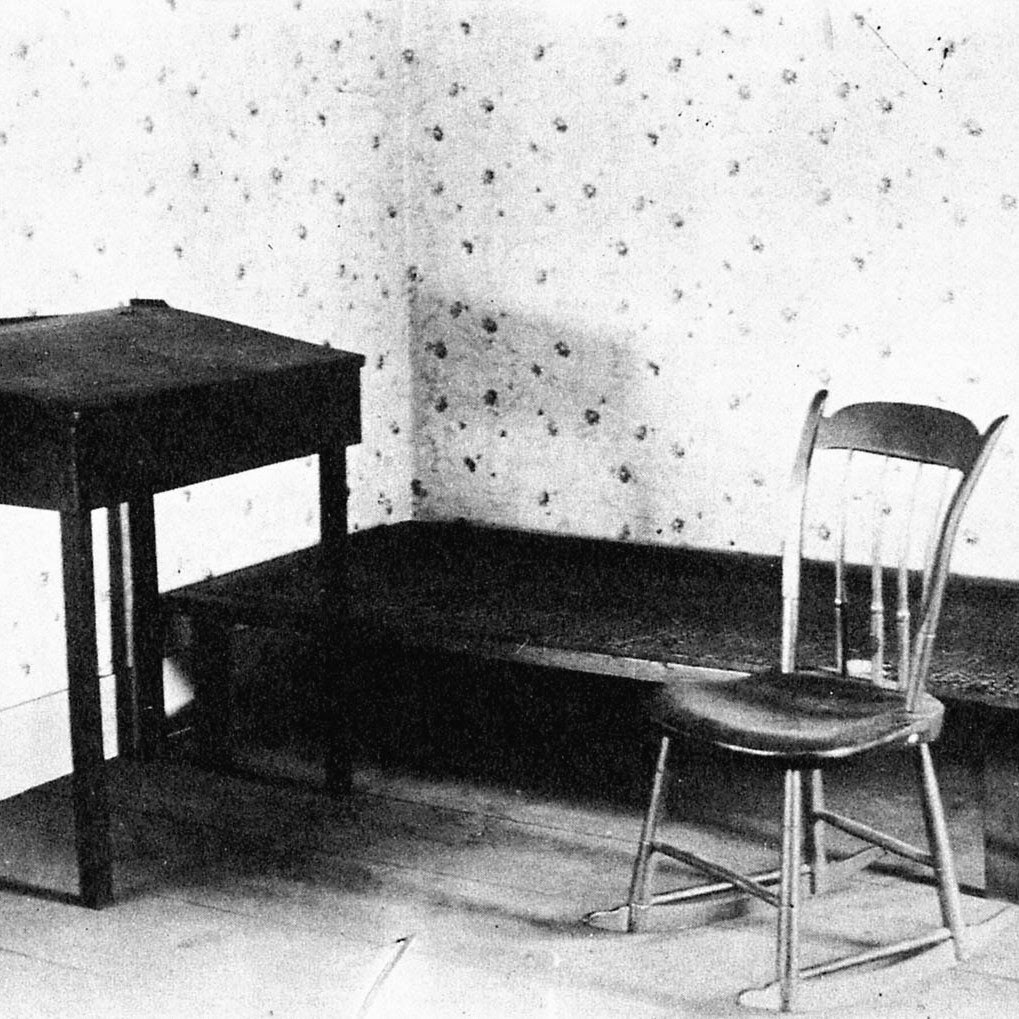 An empty desk and chair in a sparse room.