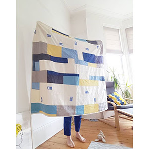 a photograph of a person holding a quilted blanket.