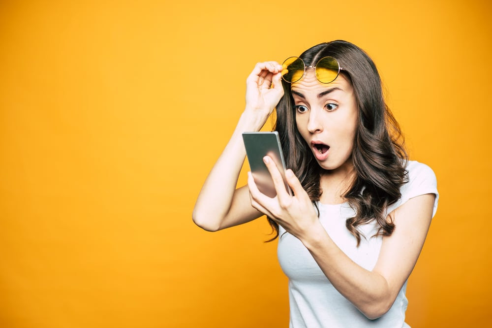 Woman looking at her phone is disbelief Woman looking at her phone is disbelief