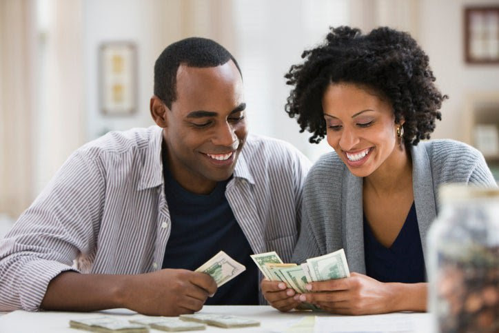 A couple smiles as they count money.