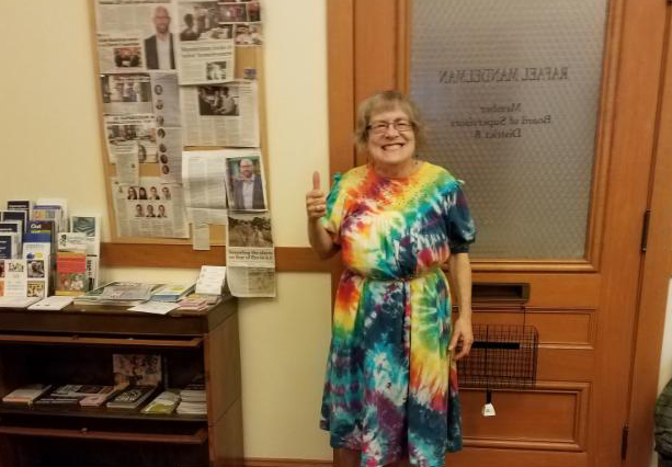woman in a tye dyed dress with a thumbs up 