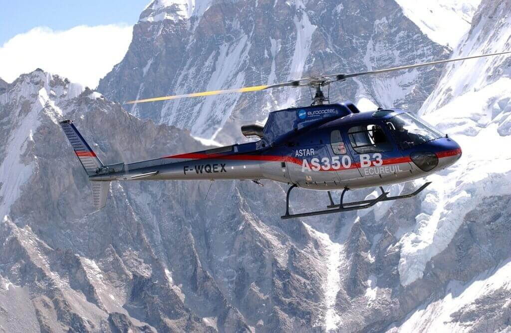 H125 helicopter in flight, with mountains in background