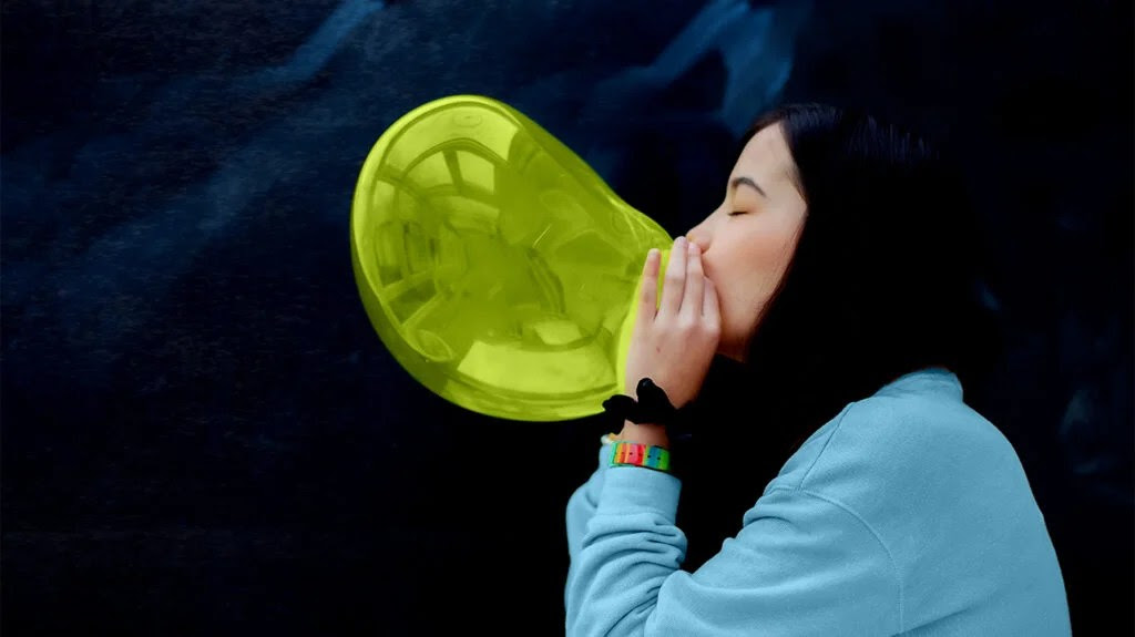 a woman blowing up a balloon to representing reducing bloating