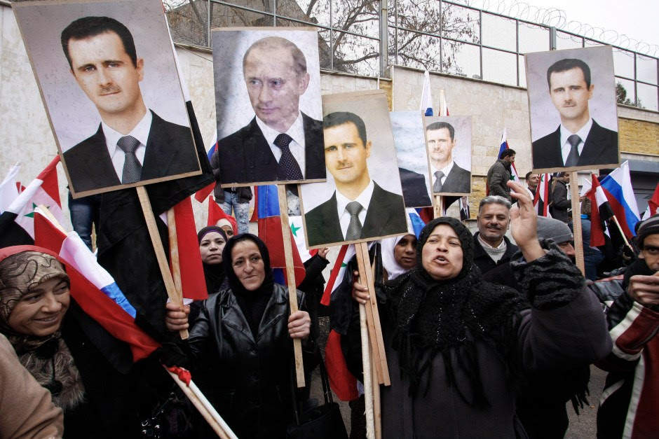 FILE - In this Sunday, March 4, 2012 file photo, Syrians hold posters of Syrian President Bashar Assad, far left, and Russian President Vladimir Putin, second left, during a pro-Syrian goverment protest in front of the Russian Embassy in Damascus, Syria. In ramping up its military involvement in Syria's civil war, Russia appears to be betting that the West, horrified by Islamic State's atrocities, may be willing to tolerate Assad for a while, perhaps as part of a transition. (AP Photo/Muzaffar Salman, File)