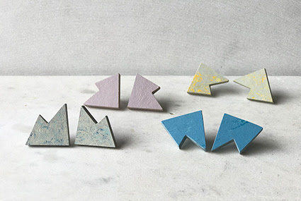 A photograph of four pair of earrings by Roslyn Leitch. They are displayed against a white marbled background, and are different colours, clockwise top to bottom: pink, light grey and yellow, grey and blue, and blue.