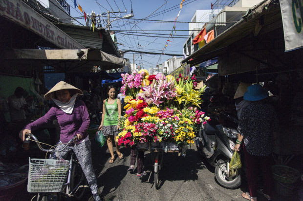 Shoppers walk past a flower vendor on a bicycle on the streets of Ho Chi Minh City earlier this year. The country is seeing a sizable influx of private money.