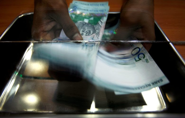 A money changer counts ringgit at a shop in Putrajaya, outside Kuala Lumpur, October 26, 2007. REUTERS/Bazuki Muhammad/File Photo      - RTX2PSJ6
