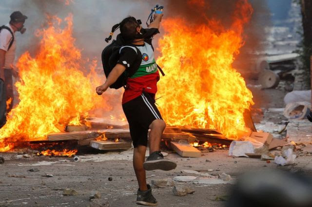 Homem lança pedras em protesto no Chile