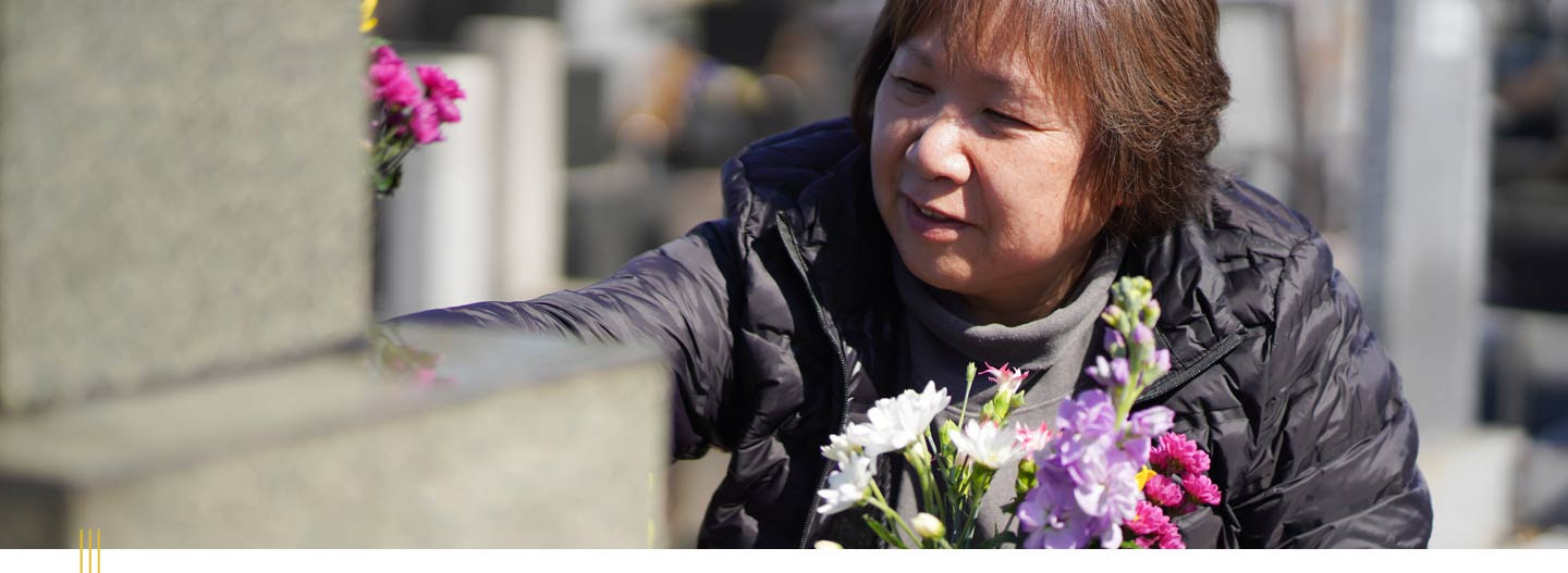 A person putting flowers on a grave.