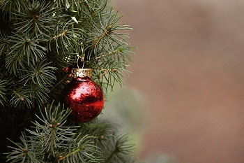 a shiny, round red and gold ornament hangs on Christmas tree, close-up view