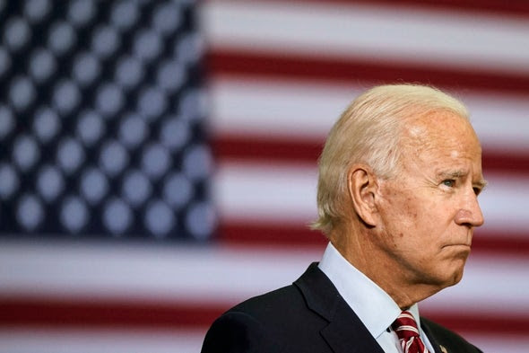Joe Biden standing in front of an American flag