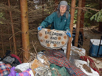 A volunteer holds up an old carpet, part of a homeless campsite cleaned up along the Boardman River.